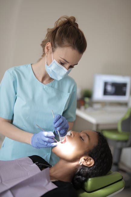 A woman is getting her teeth examined by a dentist.