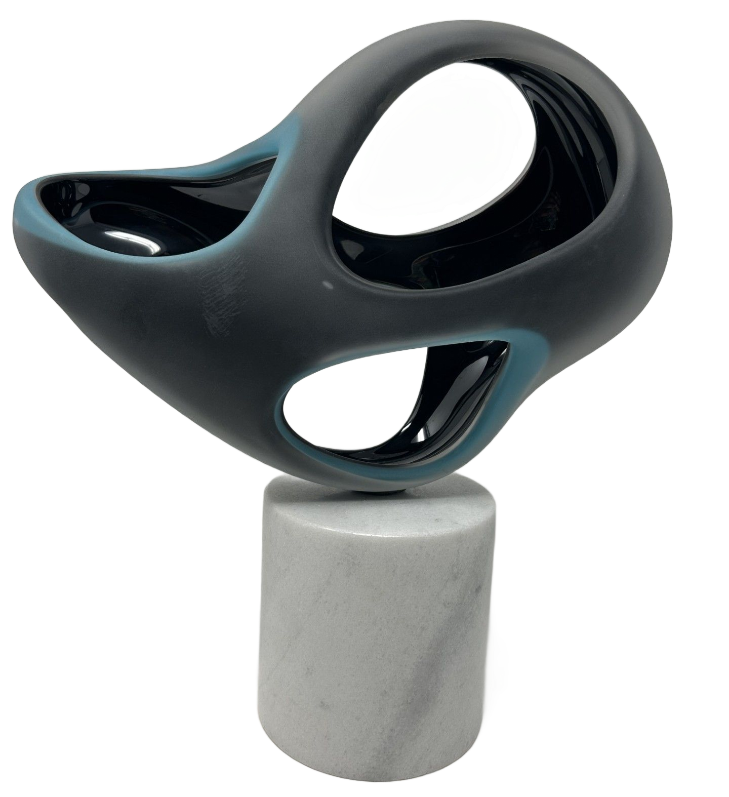 A matte gray and teal abstract ceramic sculpture with two circular cutouts, mounted on a cylindrical white marble base. 