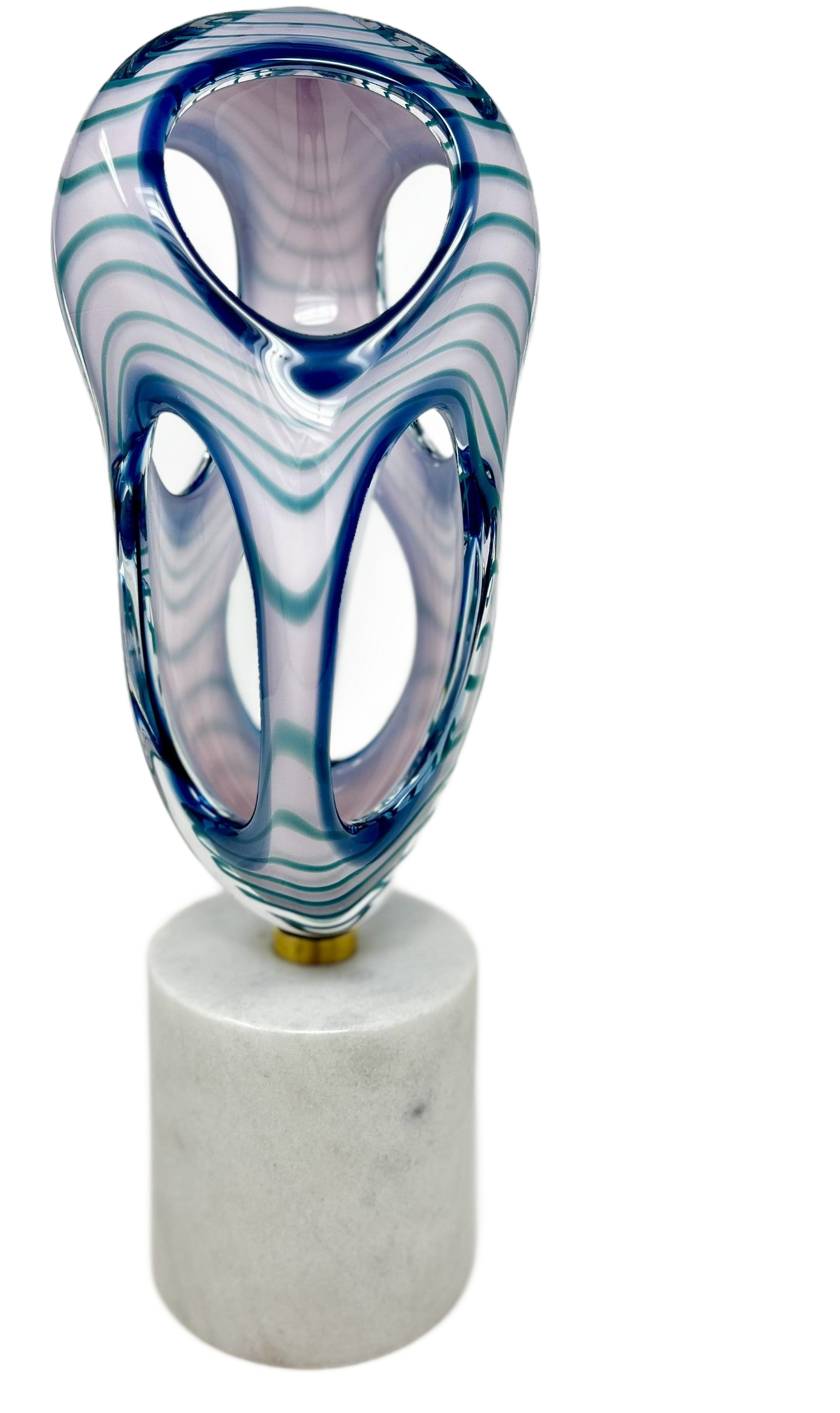 A sculptural glass piece with white and blue swirling patterns, featuring hollow openings, resting on a marble pedestal.