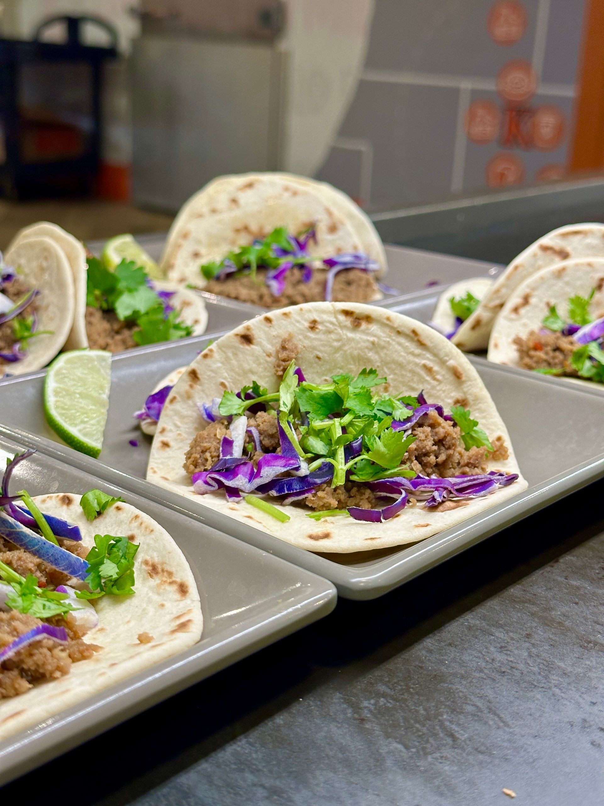 Five people in black uniforms smiling in a cafeteria setting.