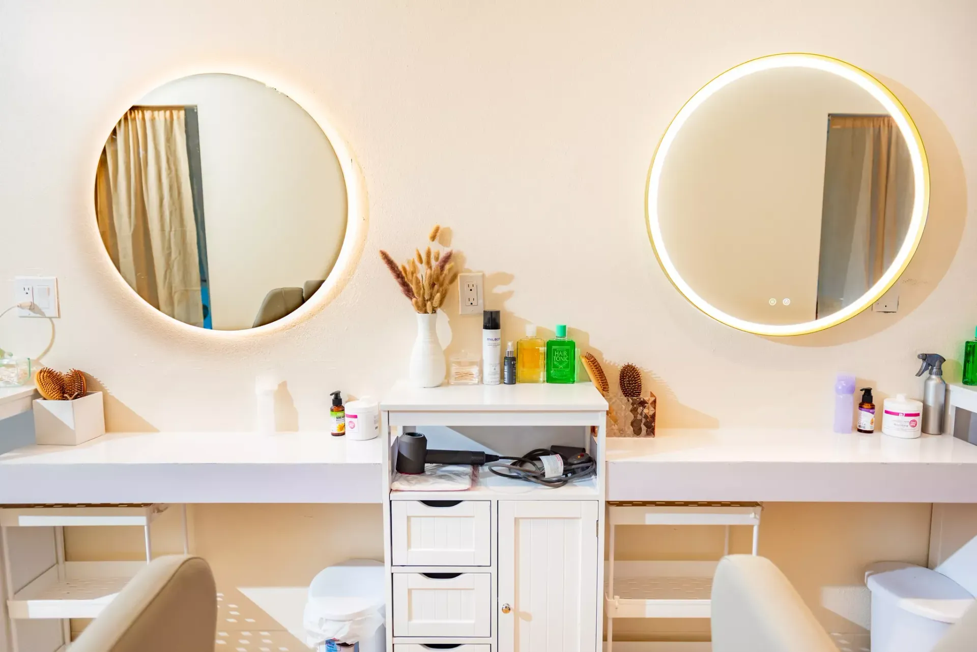 There are two mirrors on the wall in a hair salon.