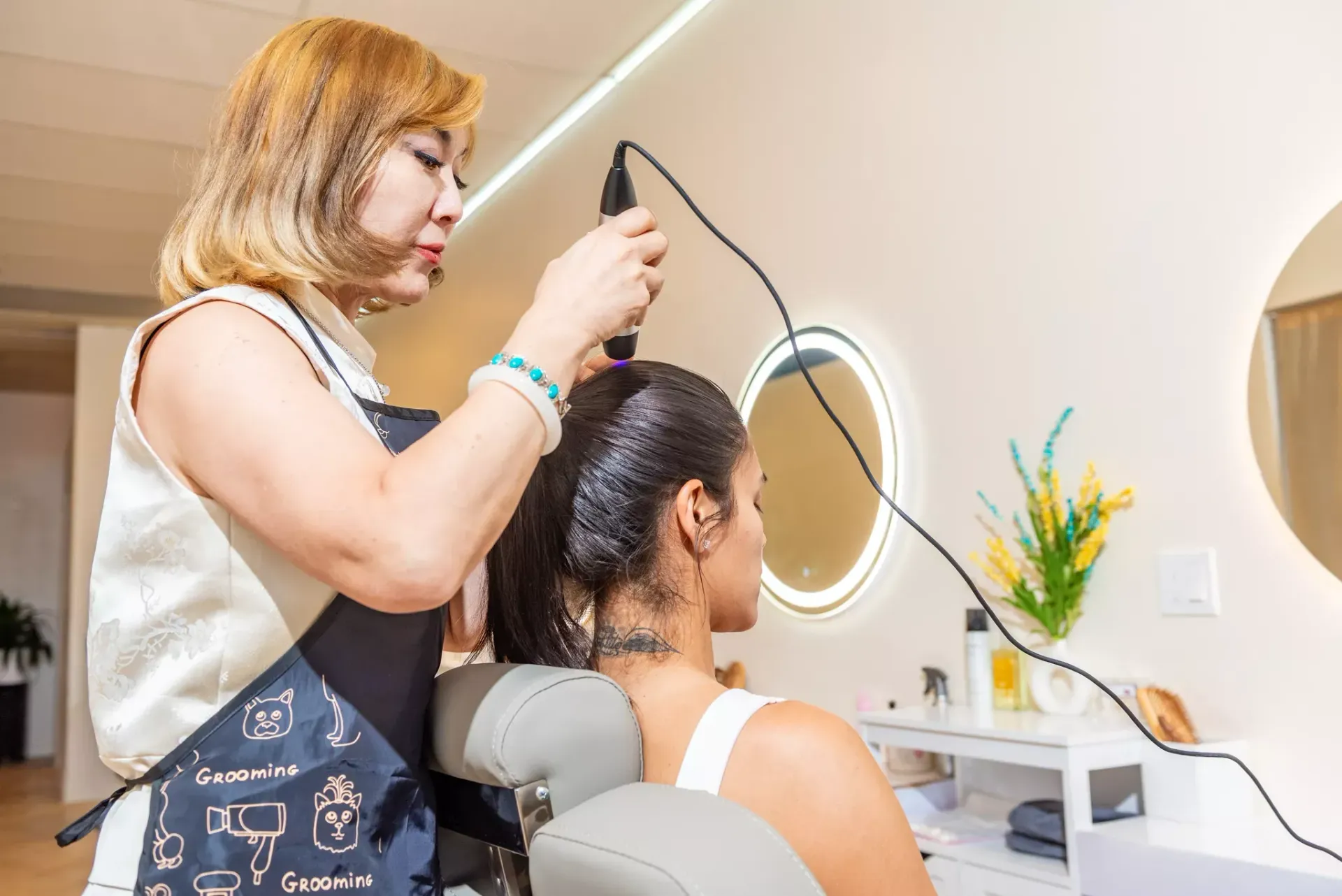 A woman is getting her hair done by a hairdresser in a salon.