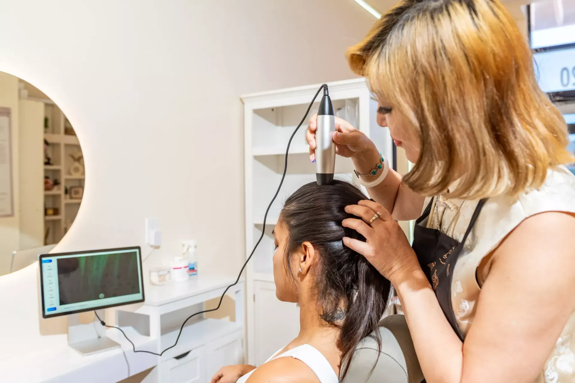 A woman is getting her hair done by a hairdresser in a salon.