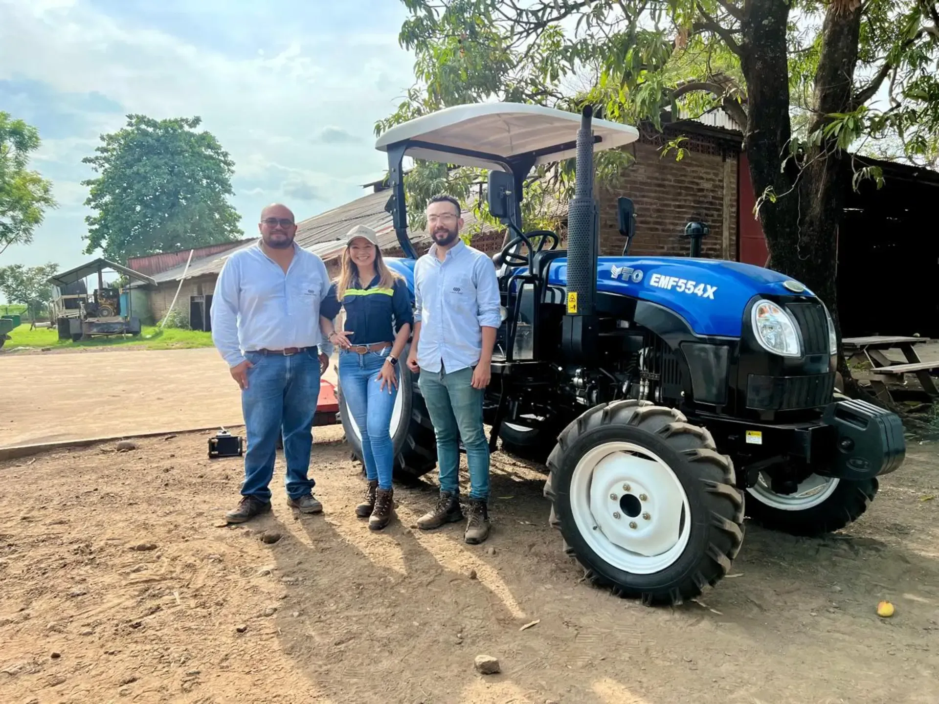 Un grupo de personas paradas junto a un tractor azul.