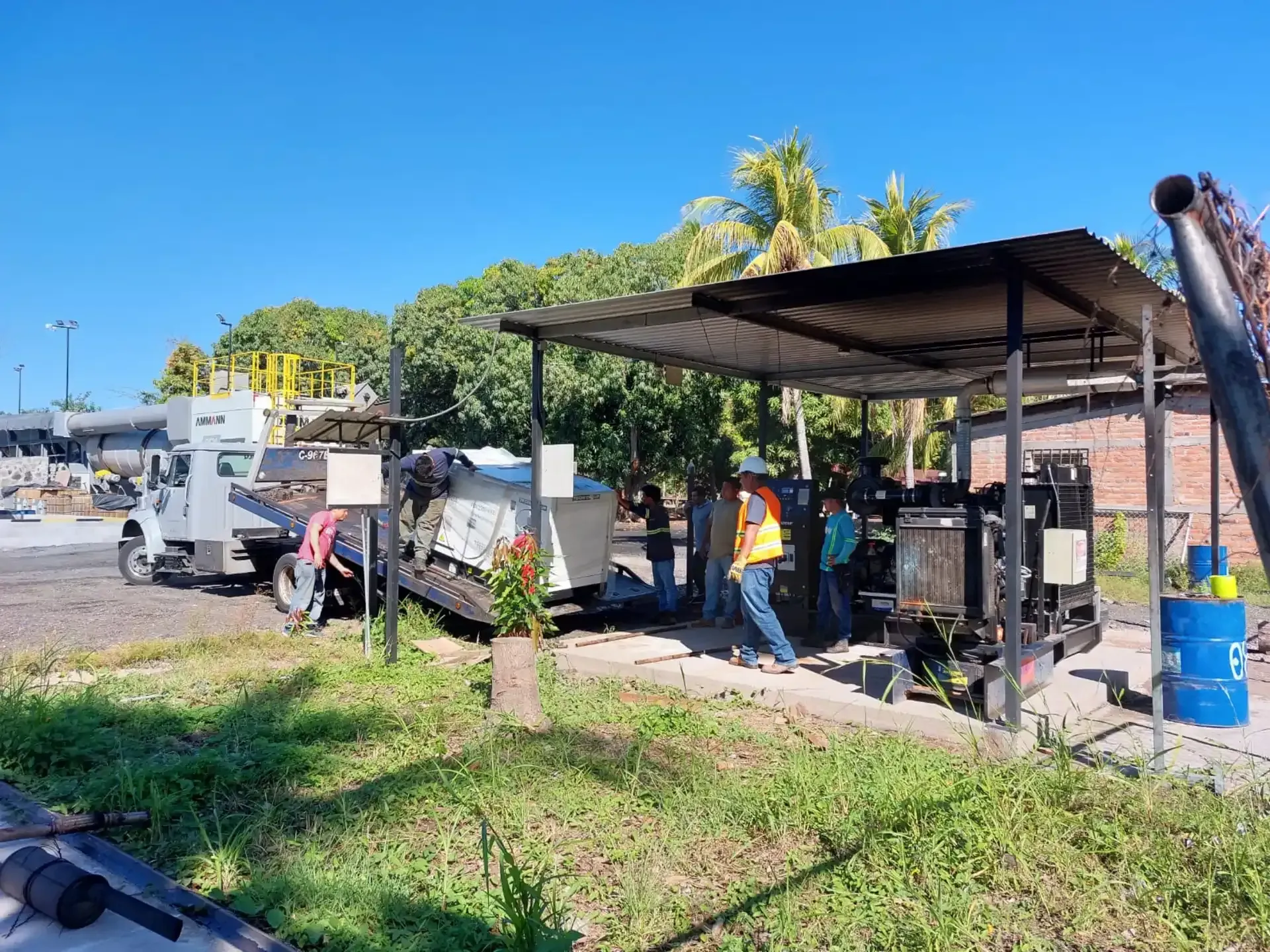 Un grupo de personas se encuentra bajo un refugio junto a un camión.