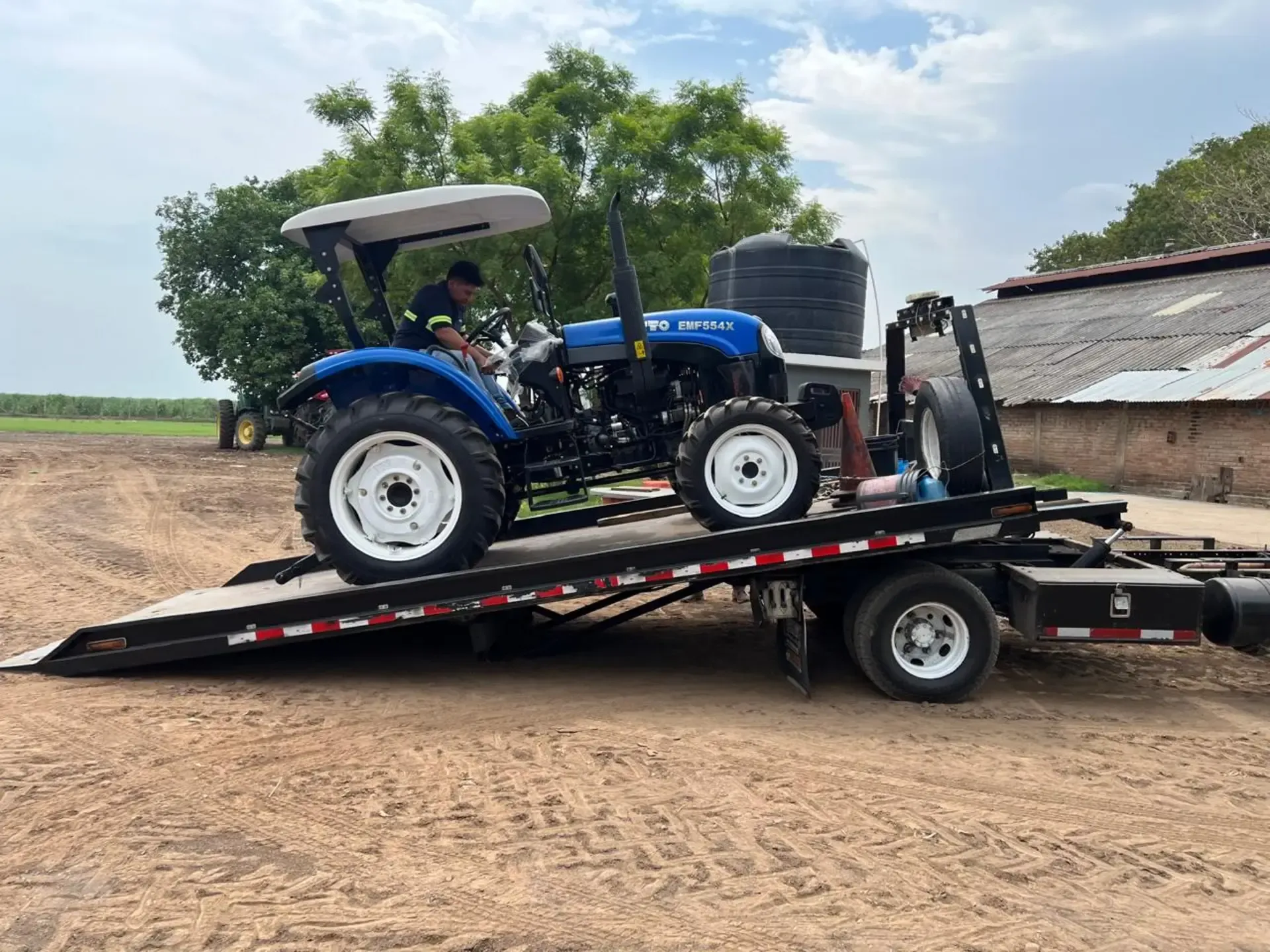 Un tractor azul está sentado encima de un remolque.