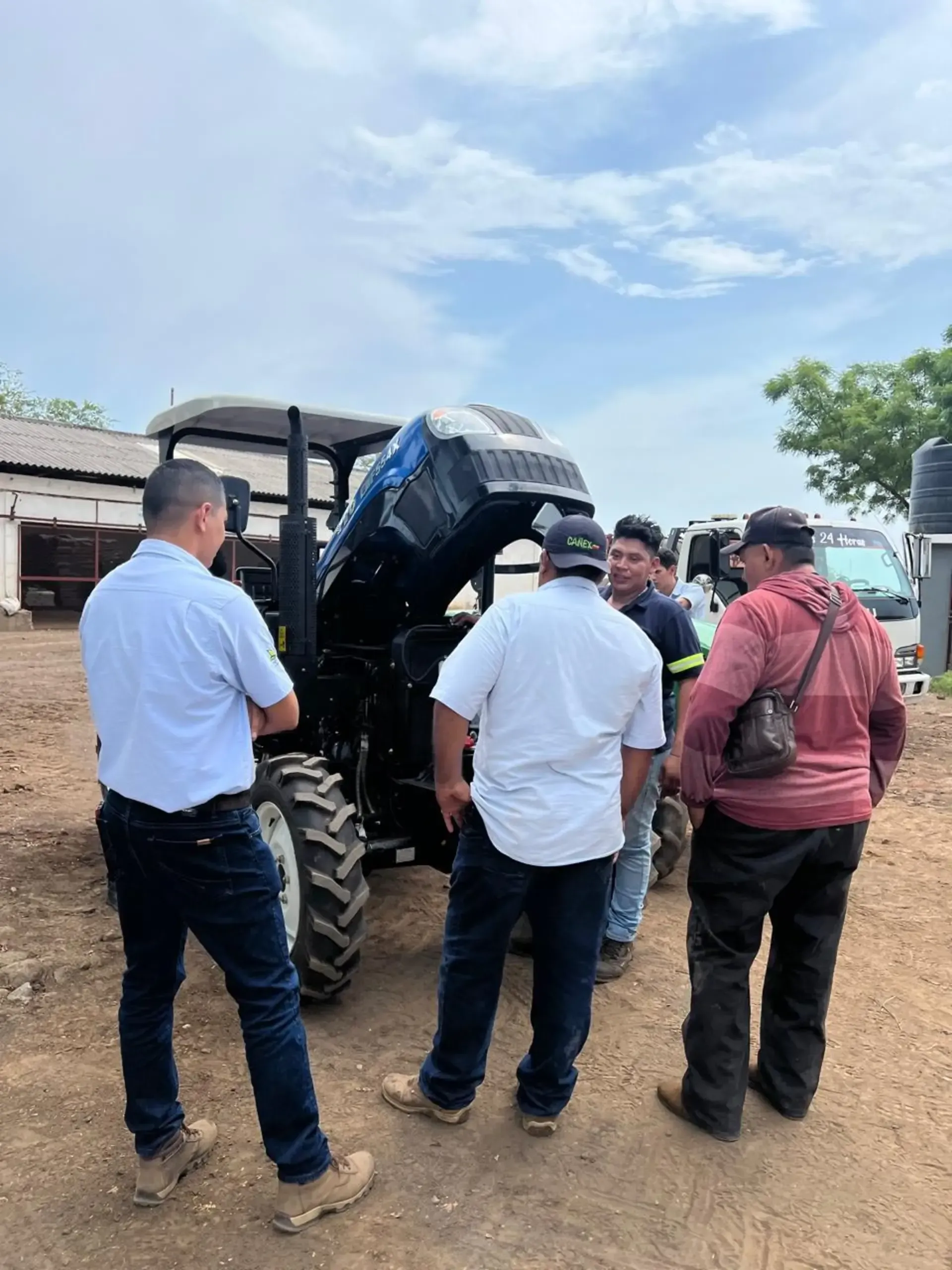 Un grupo de hombres está parado alrededor de un tractor con el capó levantado.