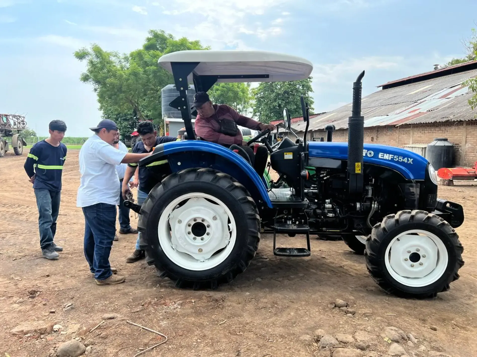 Un grupo de hombres está parado alrededor de un tractor azul.