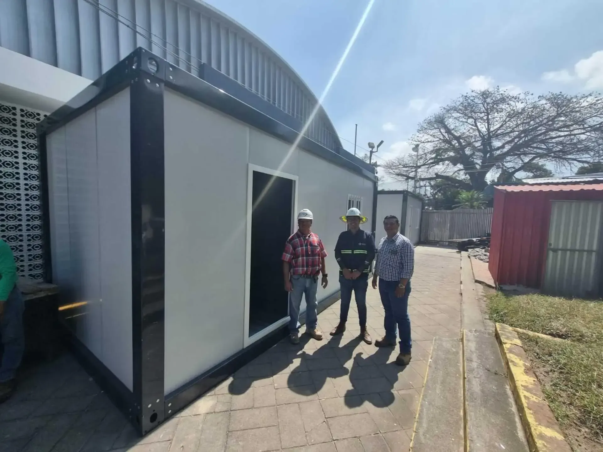 Tres hombres están parados frente a un edificio blanco