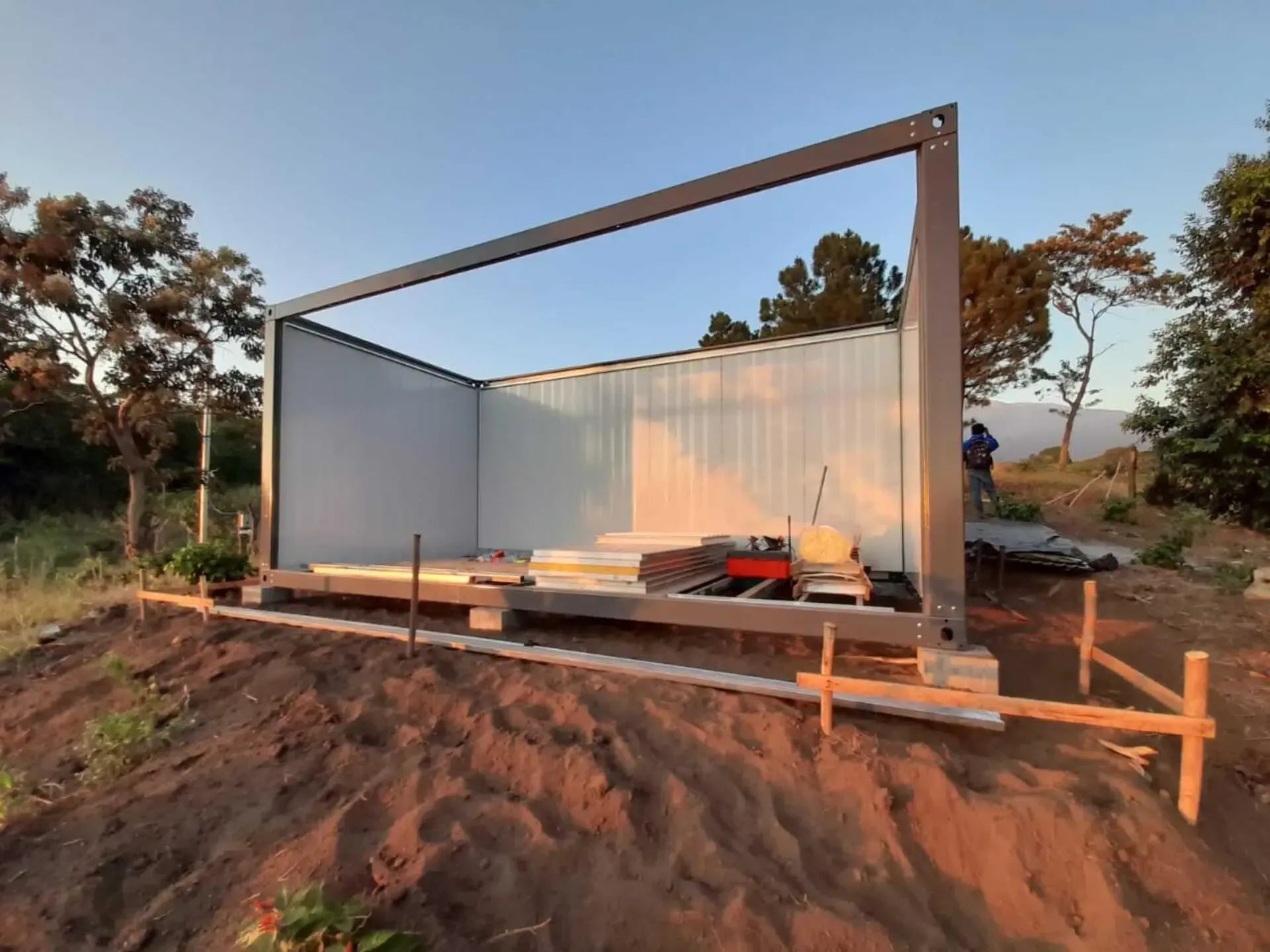 Se está construyendo un edificio blanco en medio de un campo de tierra.