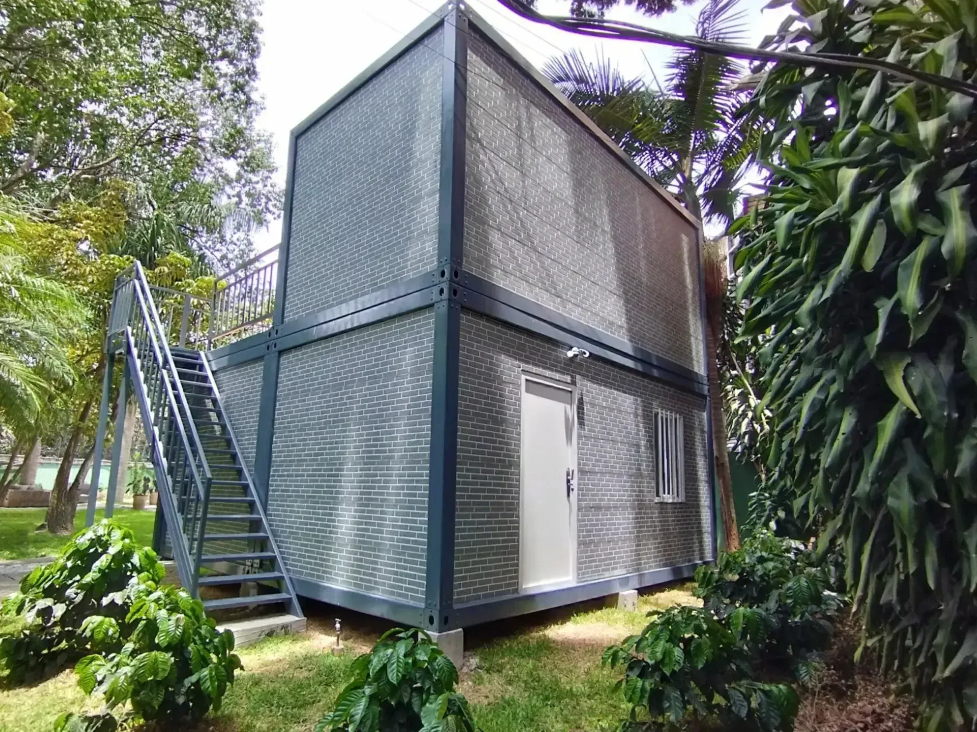 Una pequeña casa con escaleras que conducen a ella está rodeada de árboles.