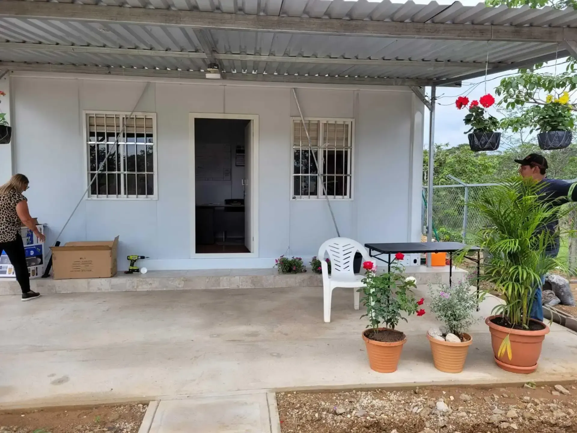 Un hombre está parado frente a una casa blanca con plantas en macetas.