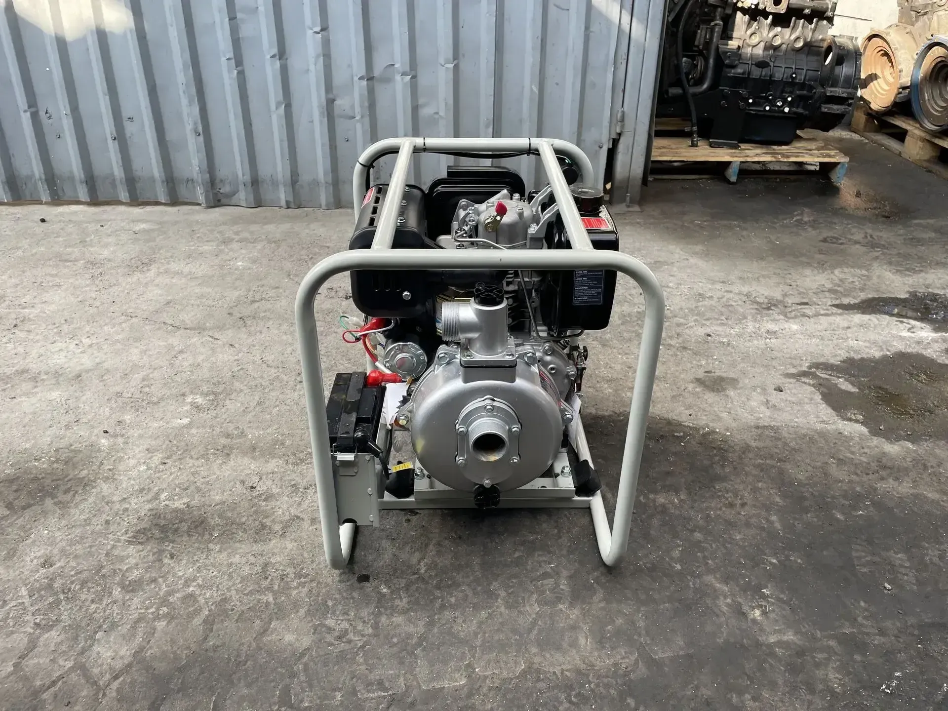 Una bomba de agua diésel está colocada en el suelo frente a un edificio.