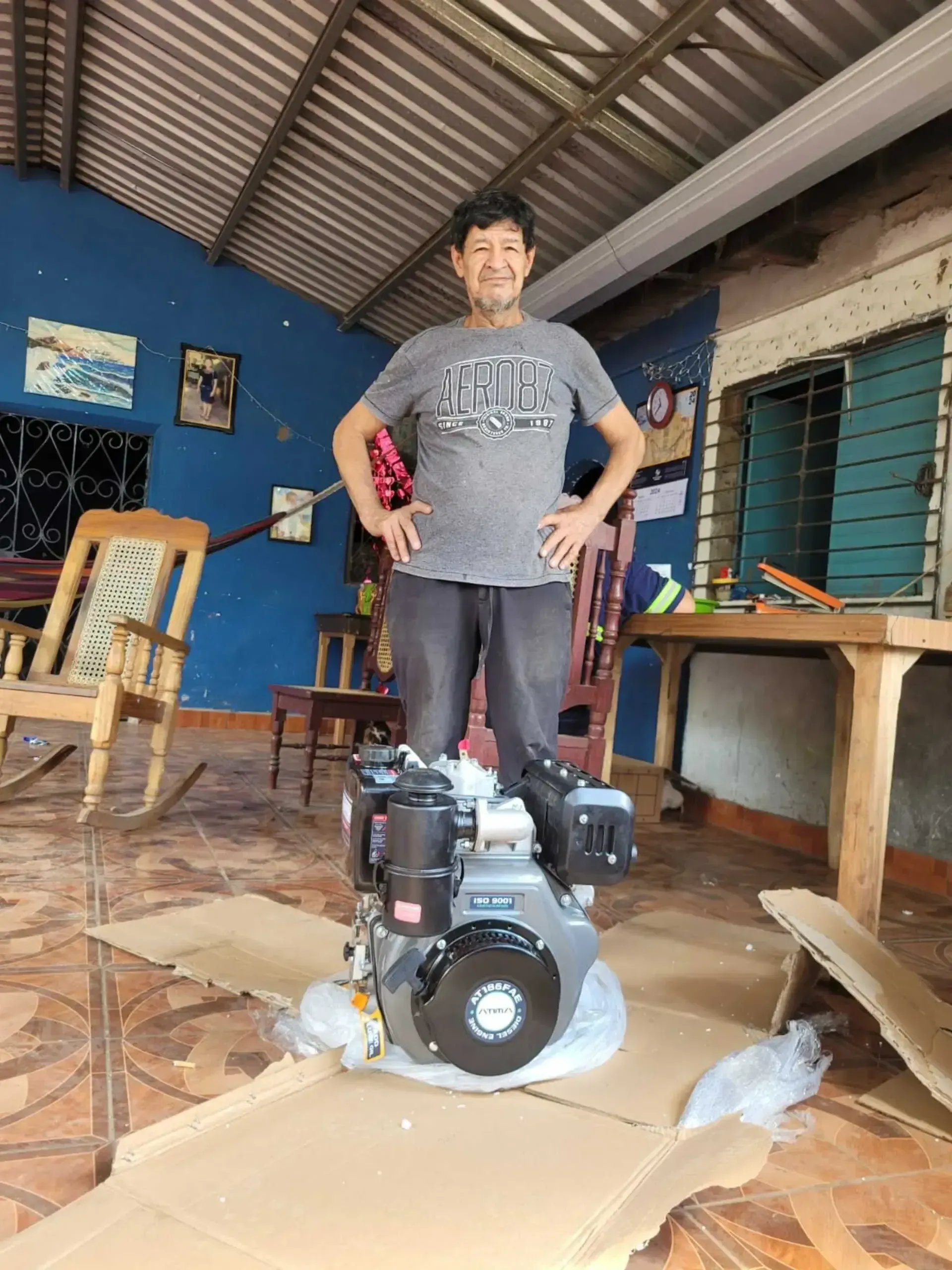 Un hombre está parado junto a un motor en una habitación.