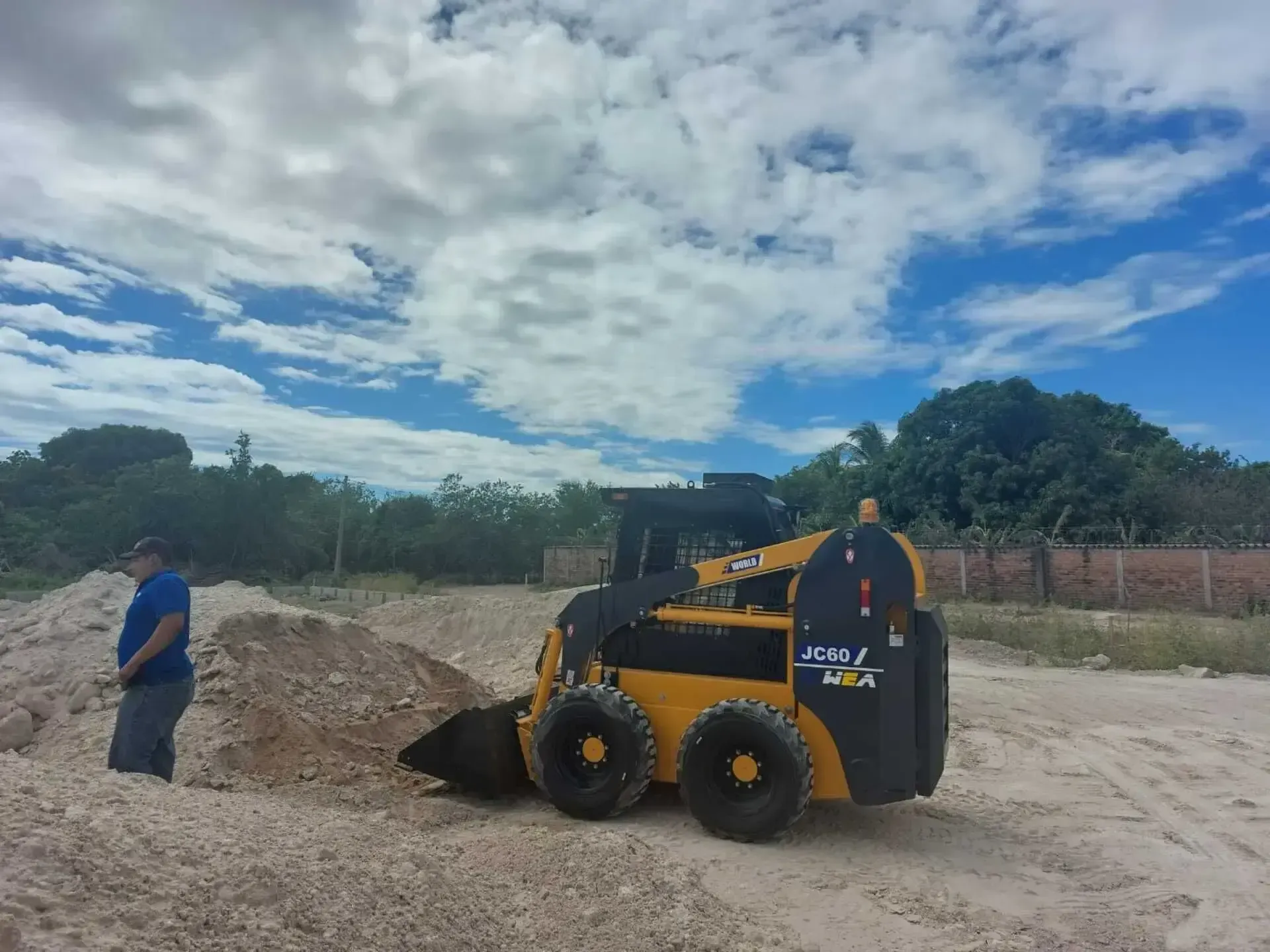 Un hombre está parado junto a una excavadora que dice gpc.