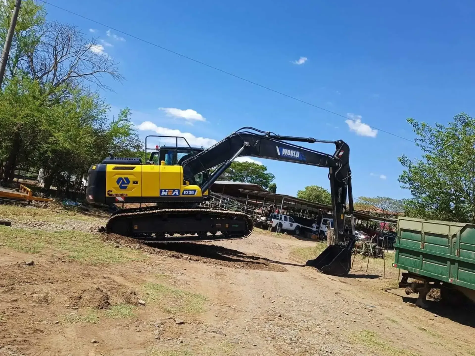 Una excavadora amarilla está estacionada al lado de un camino de tierra.