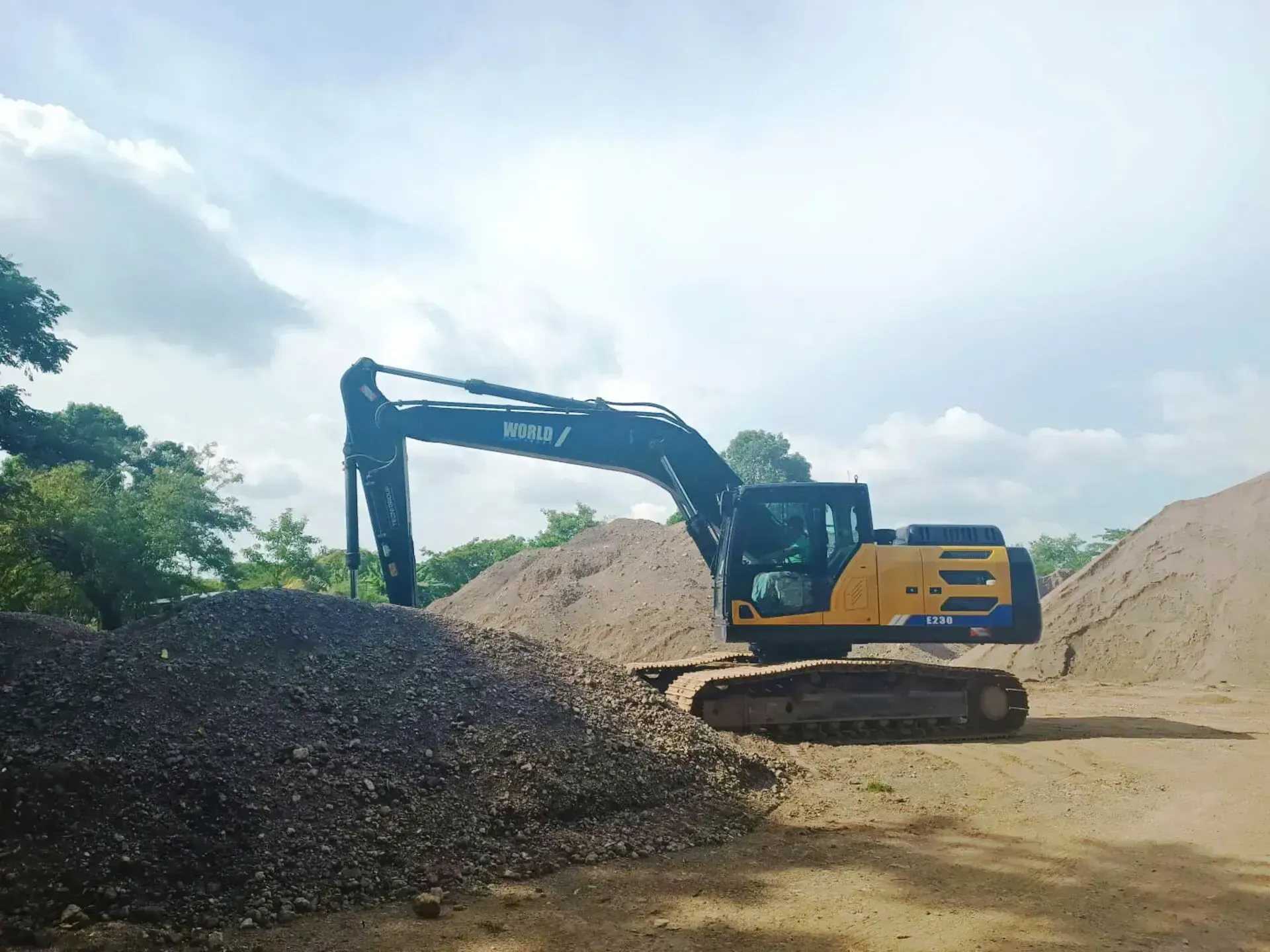 Una excavadora amarilla está sentada encima de un montón de tierra.