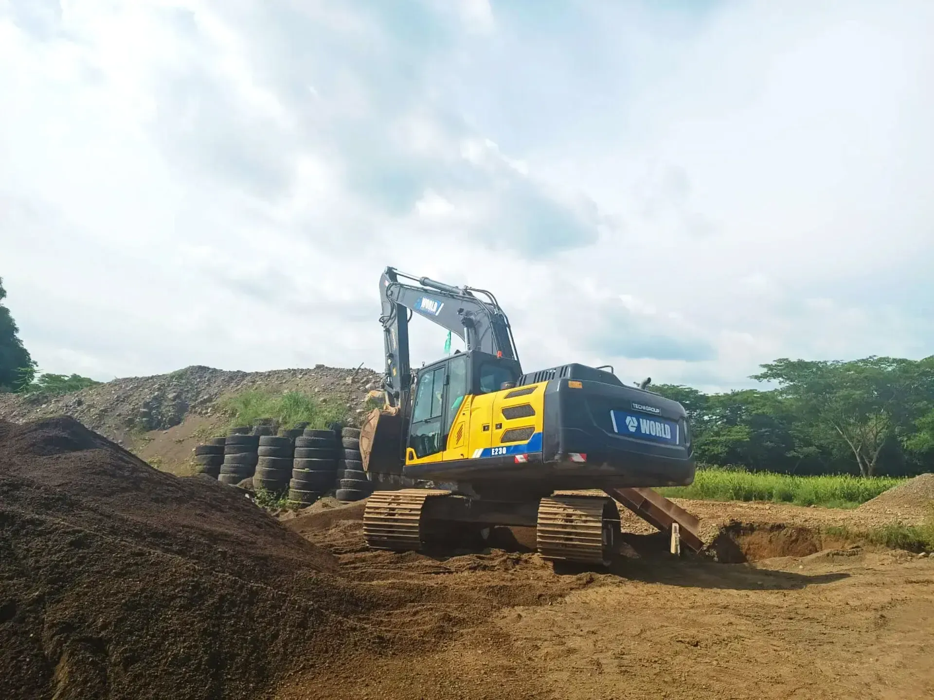 Una excavadora amarilla y negra está sentada encima de un montón de tierra.