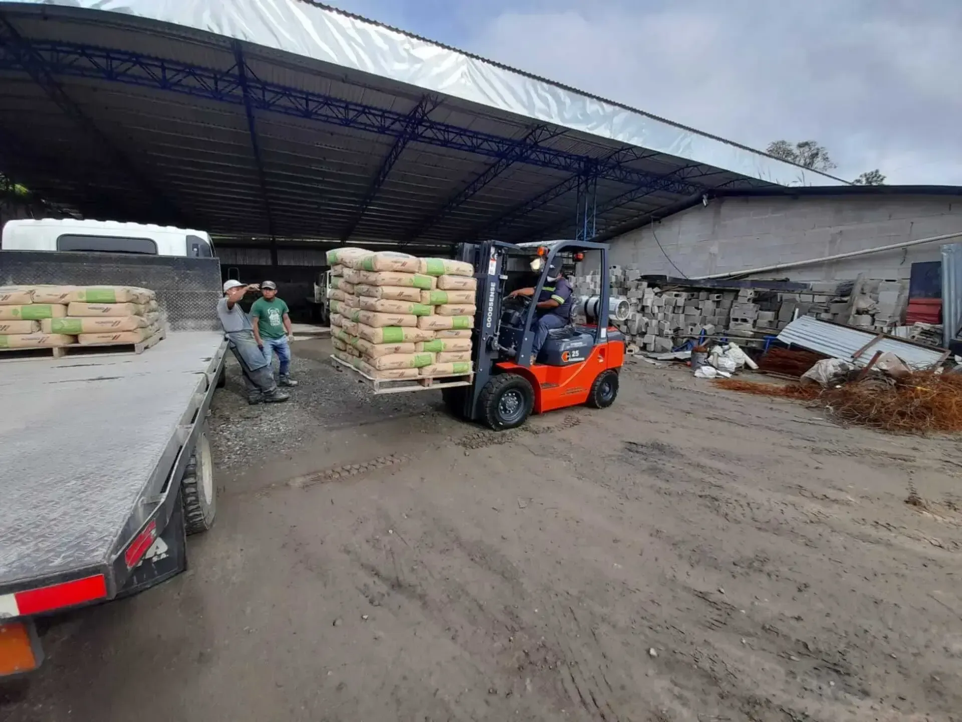Un montacargas carga un camión con sacos de cemento.
