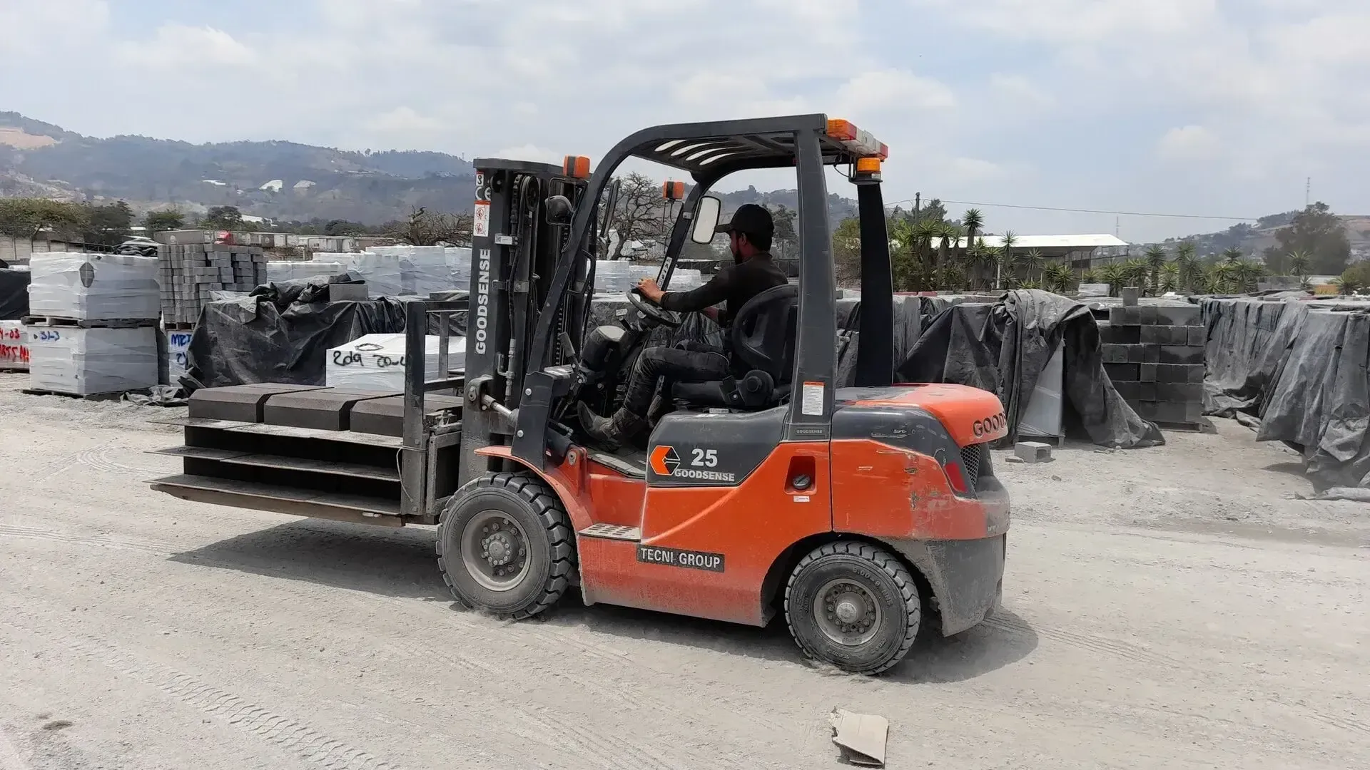 Un hombre conduce una carretilla elevadora en un campo de tierra.