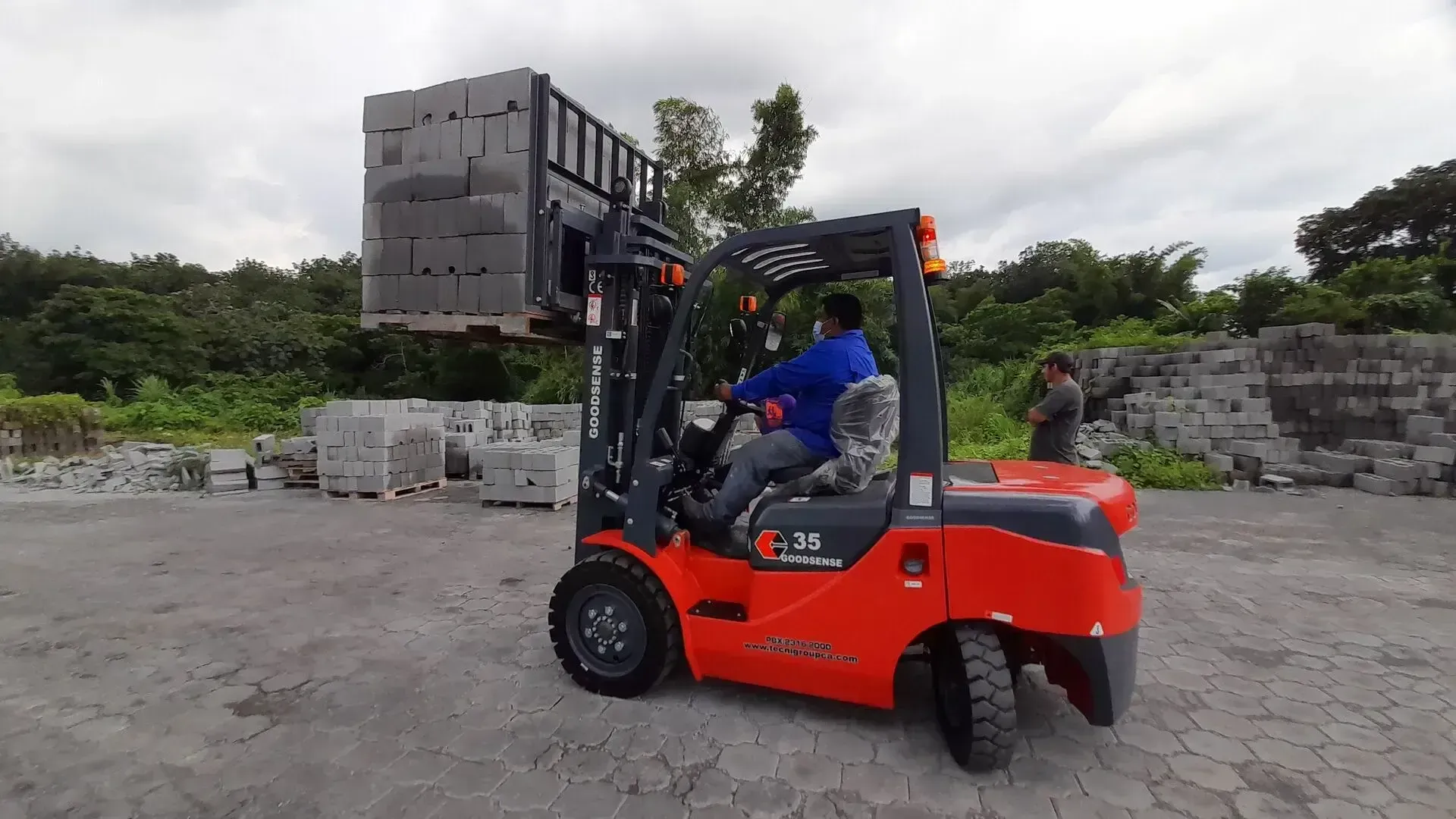 Un hombre conduce un montacargas en un estacionamiento.