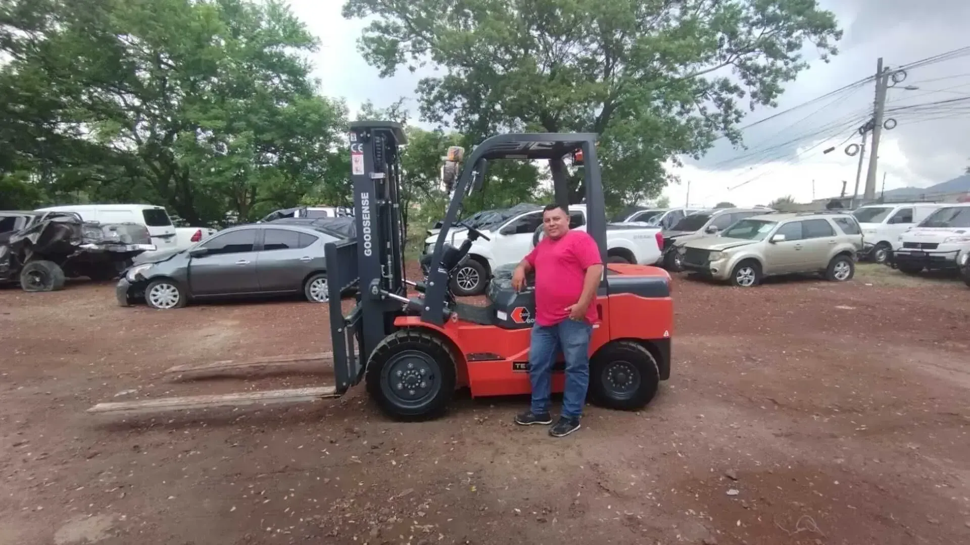 Un hombre está parado junto a un montacargas en un estacionamiento.
