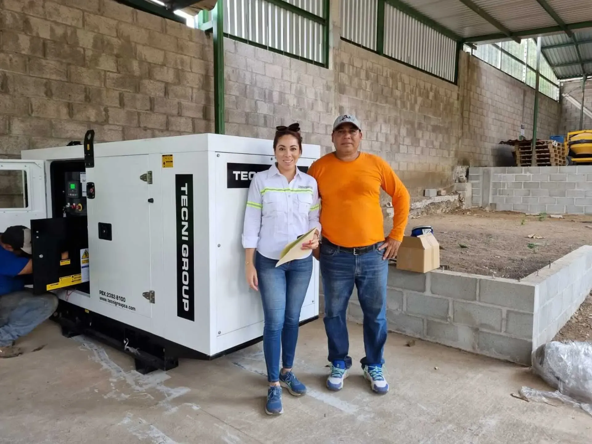 Un hombre y una mujer posan para una fotografía frente a un generador.