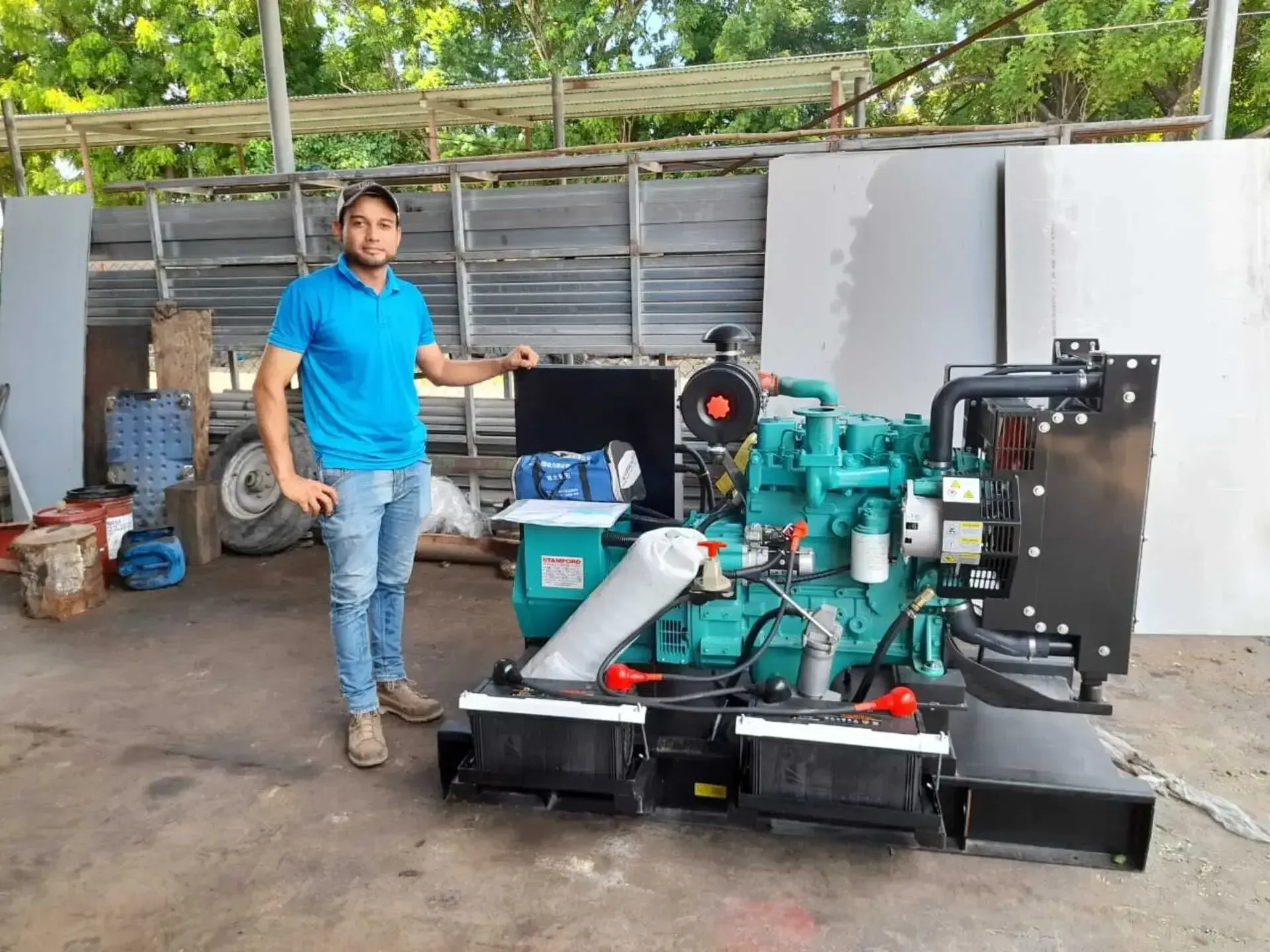 Un hombre con una camisa azul está parado junto a un generador verde.