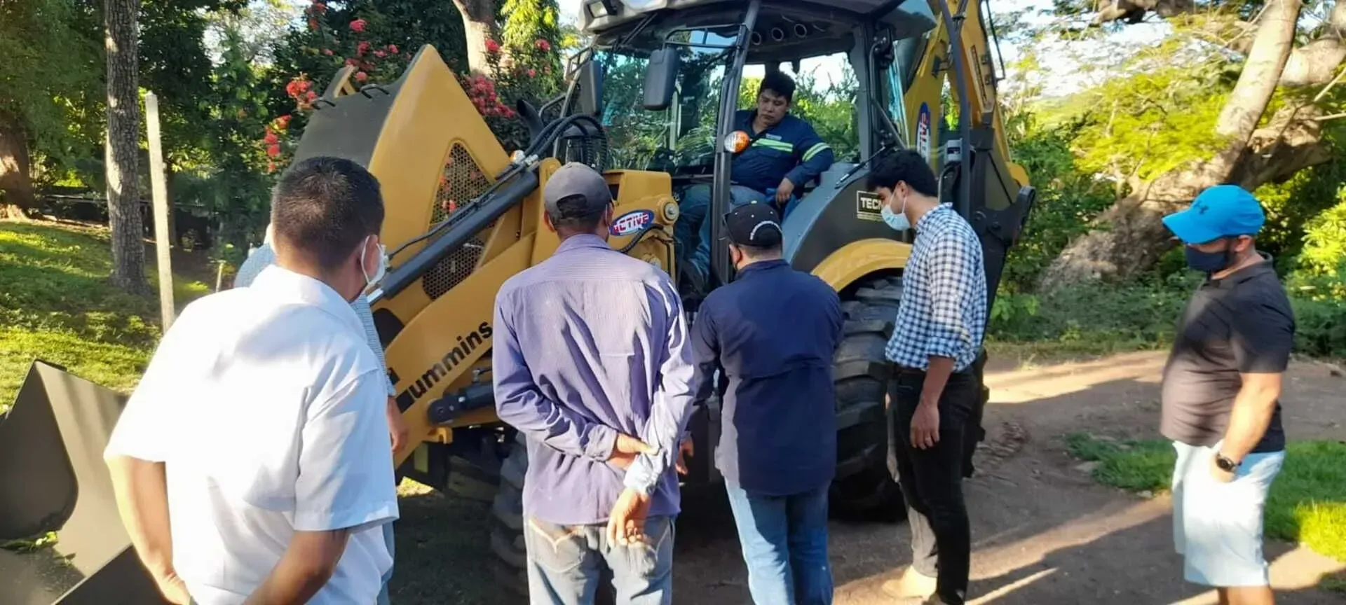 Un grupo de hombres está parado alrededor de un tractor.