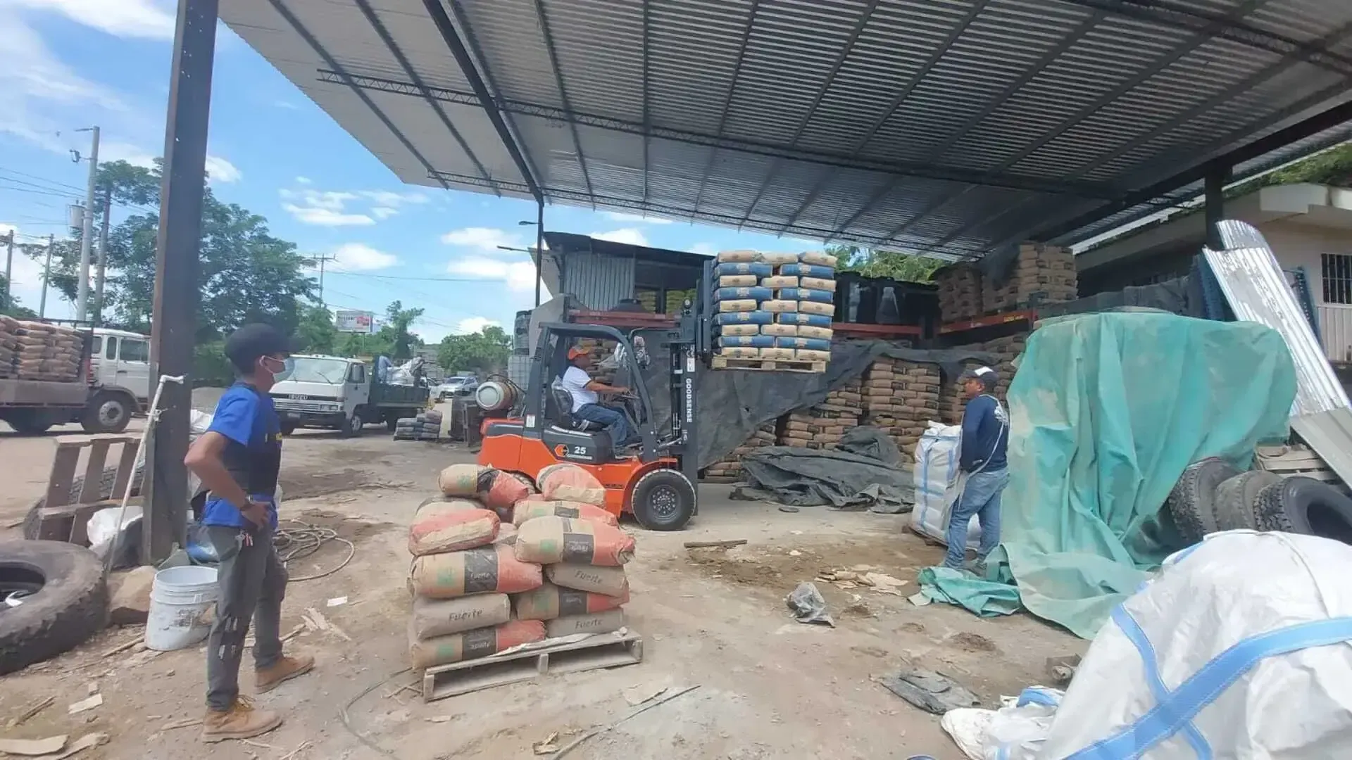 Un hombre está parado junto a un montacargas en un almacén.