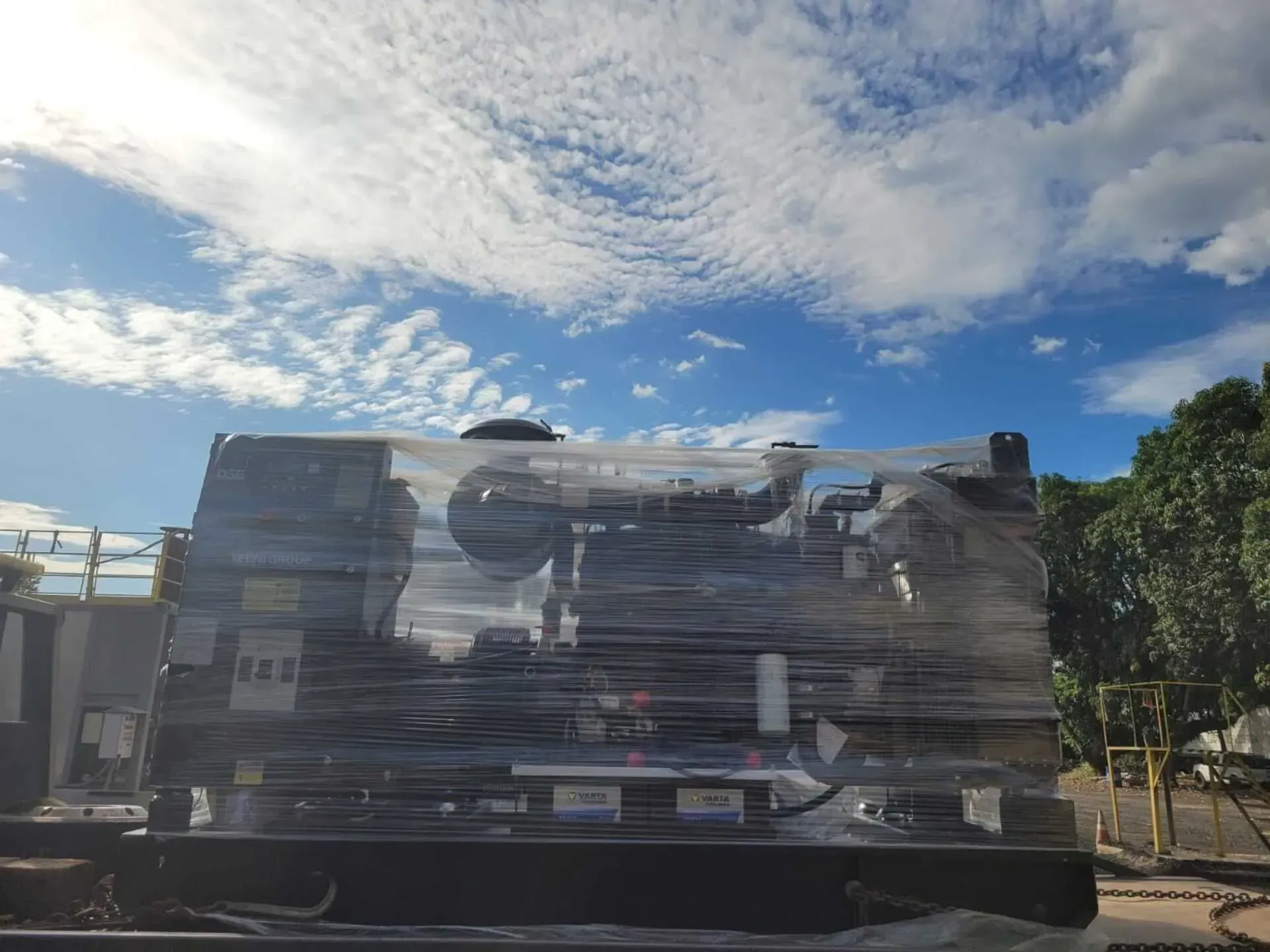 Una máquina grande está envuelta en plástico y colocada encima de un camión.