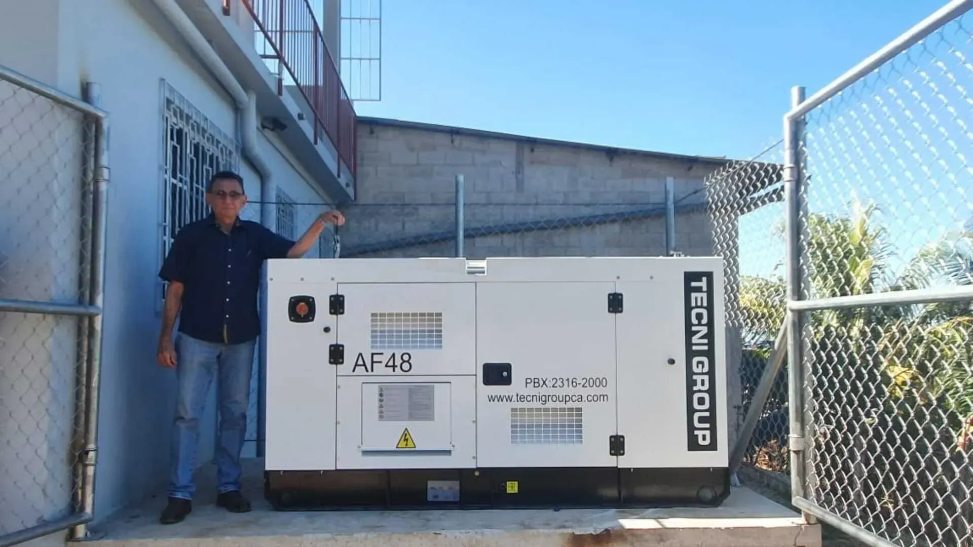 Un hombre parado al lado de un generador que dice technigroup