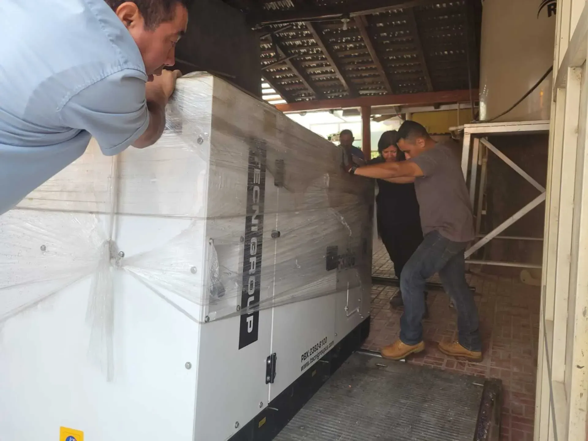 Un grupo de hombres está levantando una caja grande que dice 