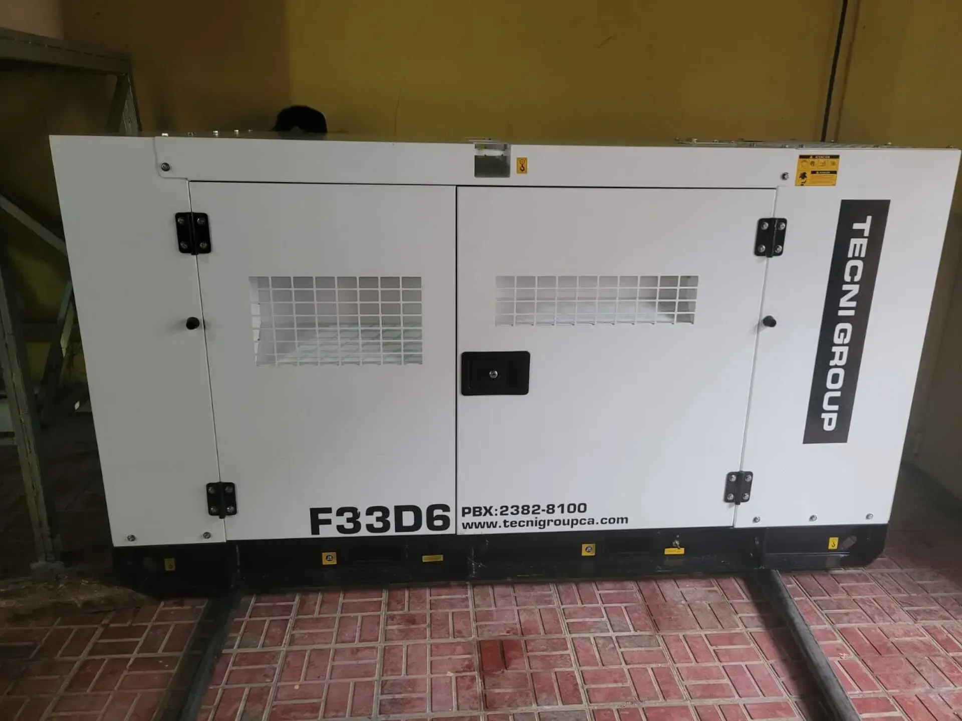 Un generador blanco está sentado sobre un suelo de ladrillo.