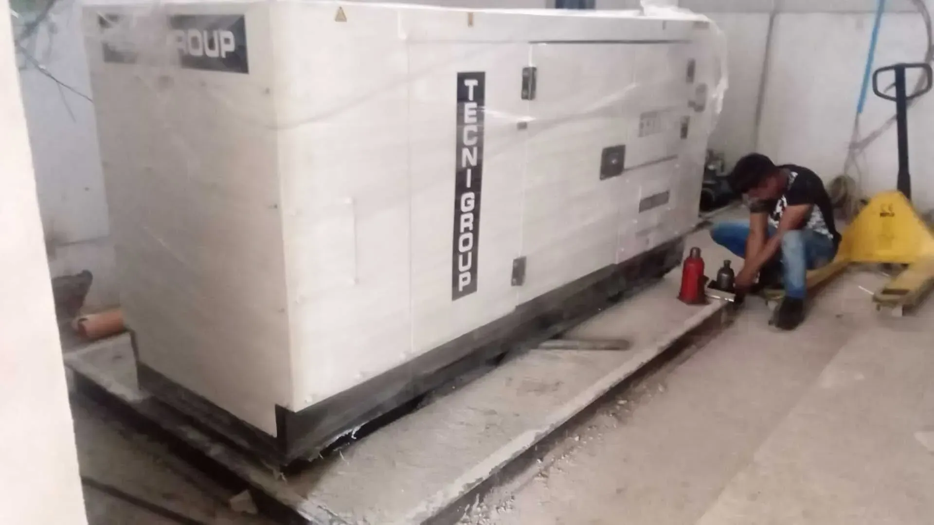 Un hombre está trabajando en un generador en una habitación.