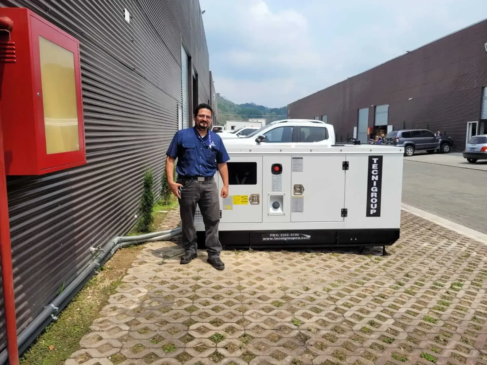 Un hombre está parado junto a un generador frente a un edificio.
