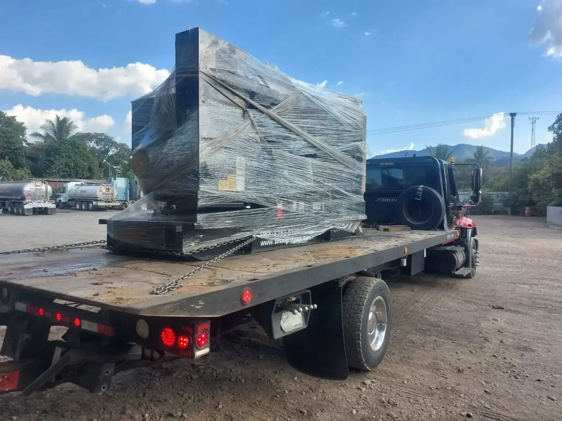 Una grúa transporta un gran trozo de mármol en su plataforma.