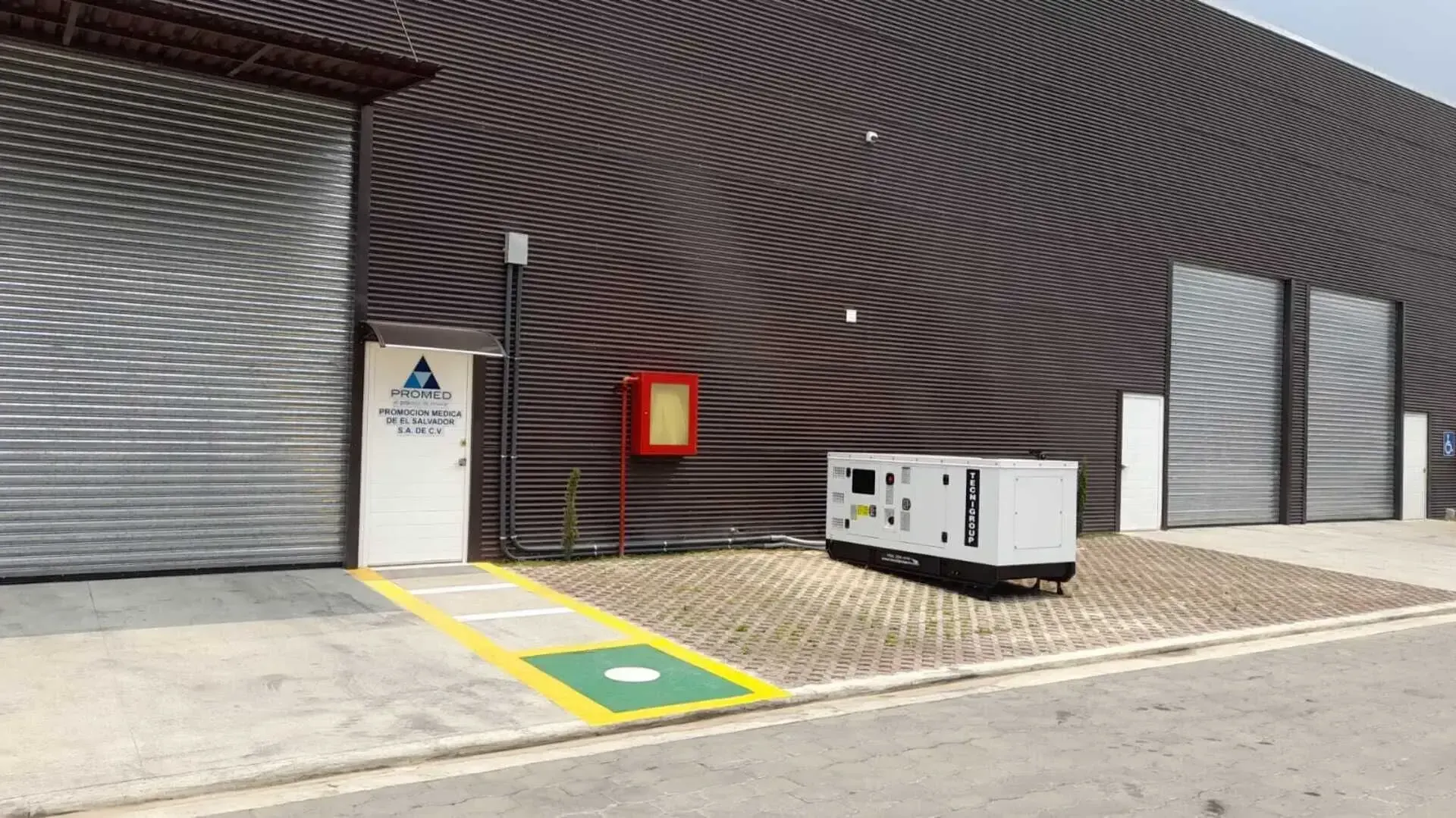 Un edificio grande con muchas puertas y un generador enfrente.