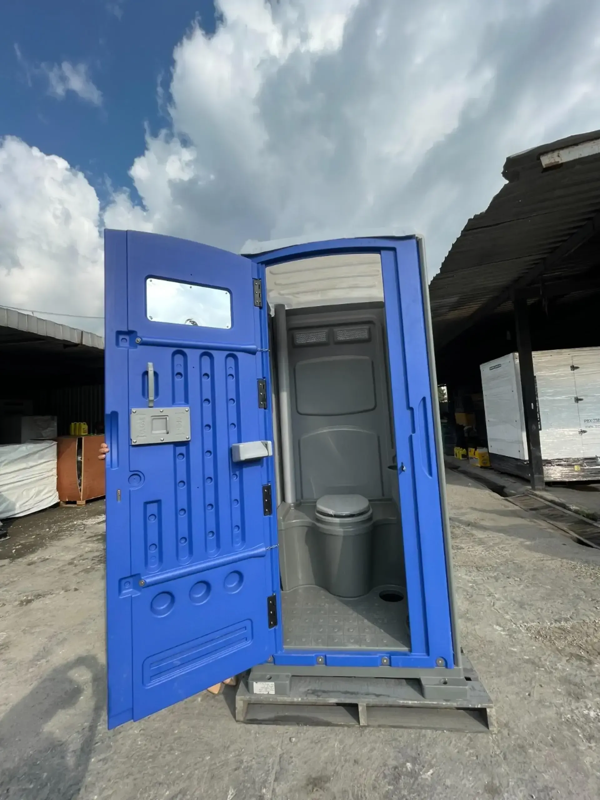 Un baño portátil azul con la puerta abierta.