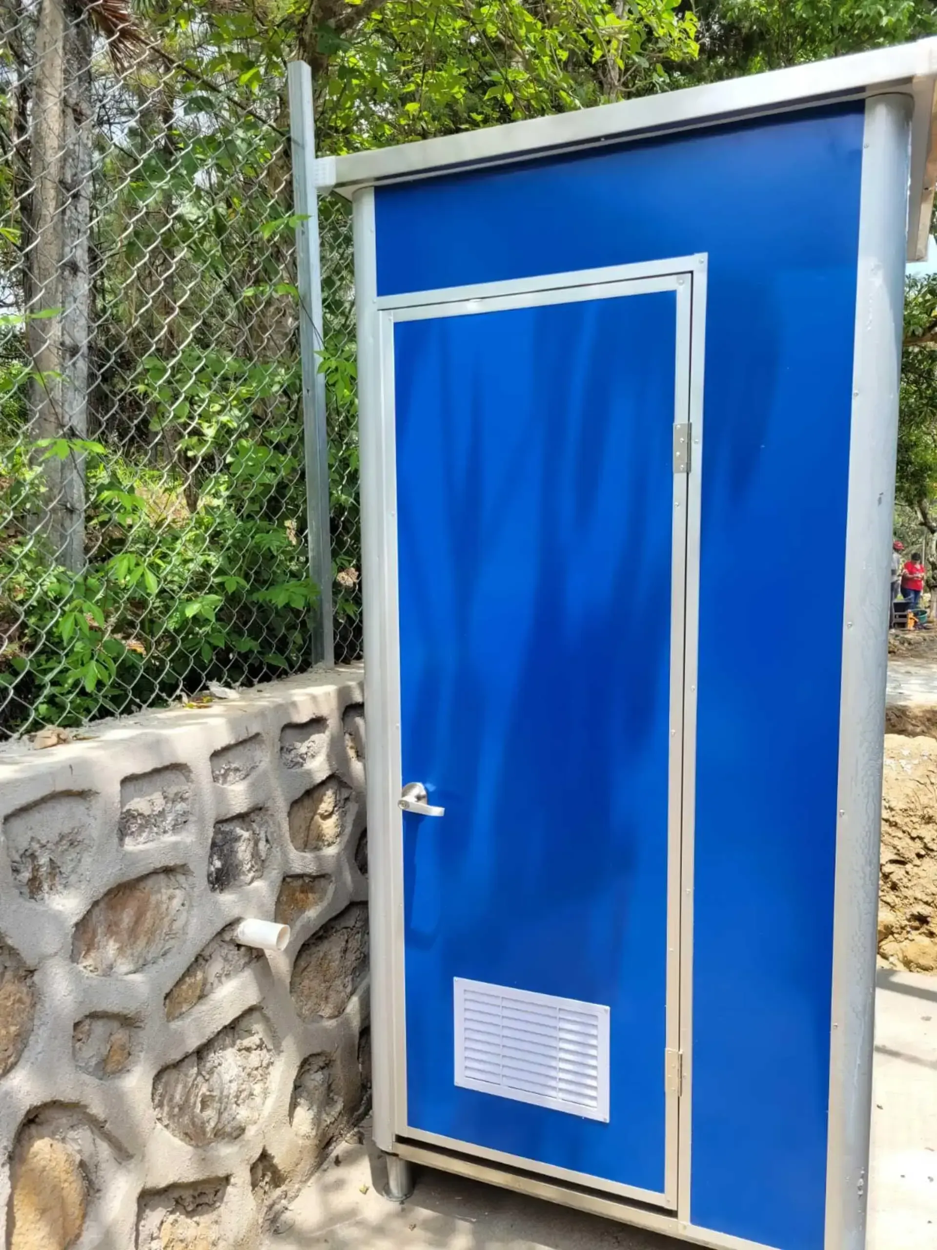 Hay una puerta azul junto a un muro de piedra.
