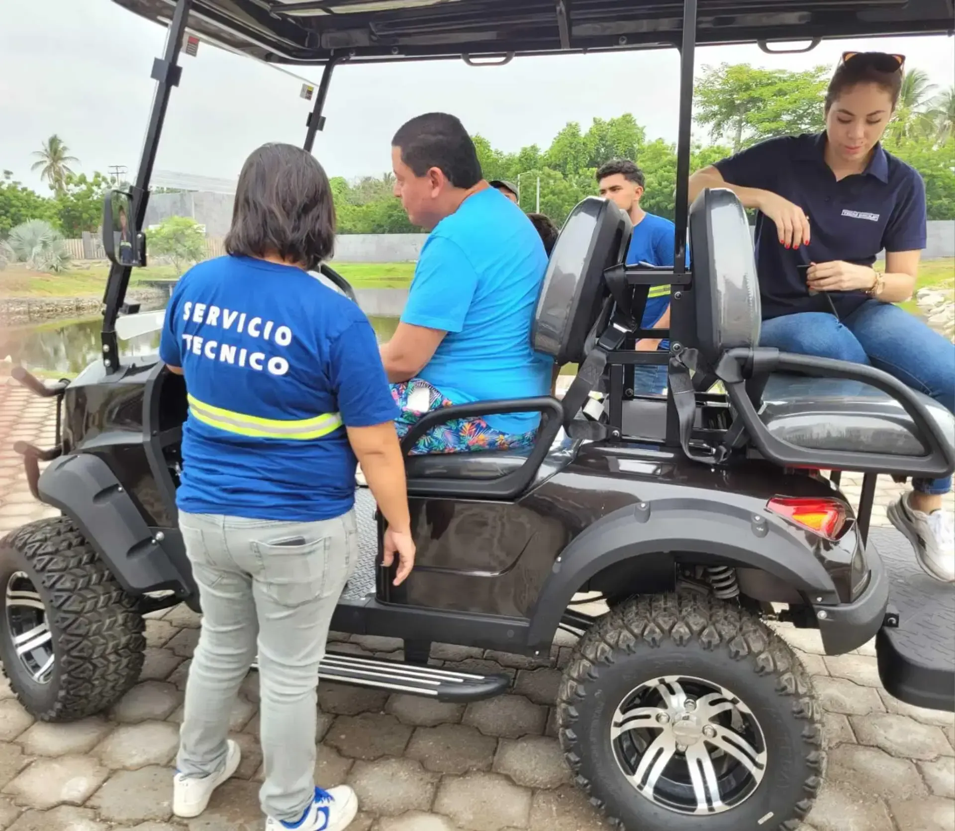 Una mujer con una camiseta de servicio técnico está parada junto a un carrito de golf