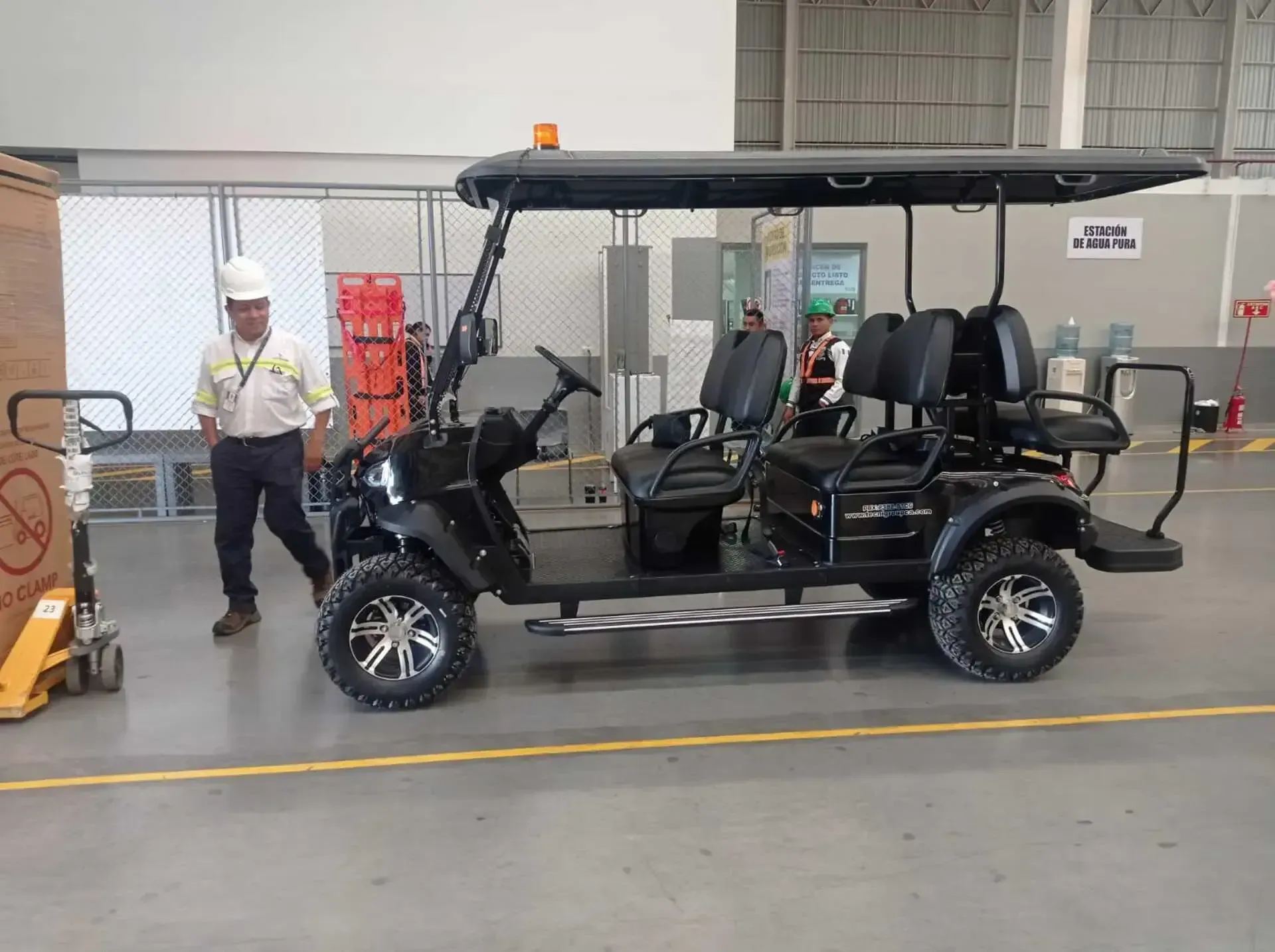 Un hombre está parado junto a un carrito de golf en un almacén.