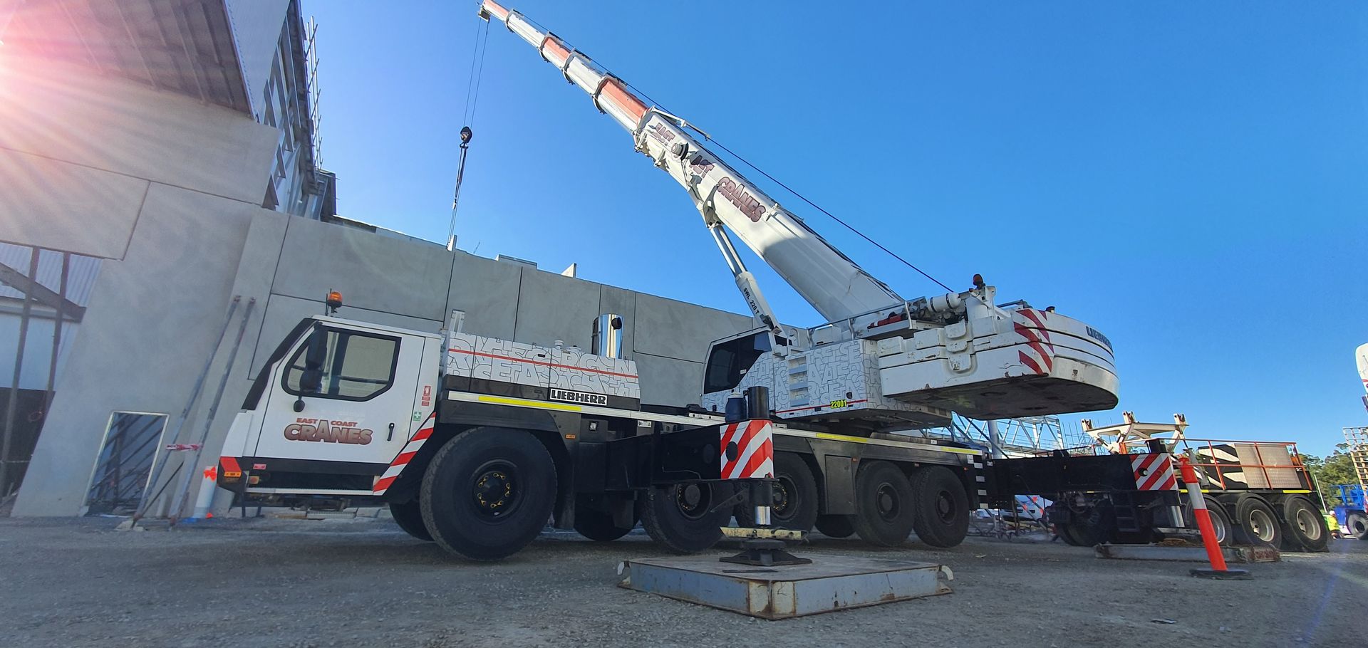A Large Crane Parked Near a Building Under a Bright Blue Sky — East Coast Cranes in Ormeau, QLD