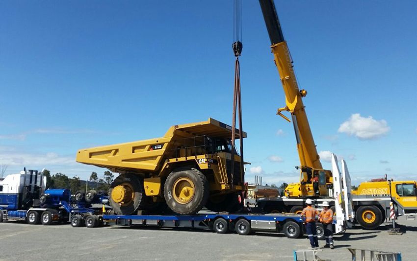 A Large Yellow Dump Truck Is Being Lifted by A Crane — East Coast Cranes in Ormeau, QLD