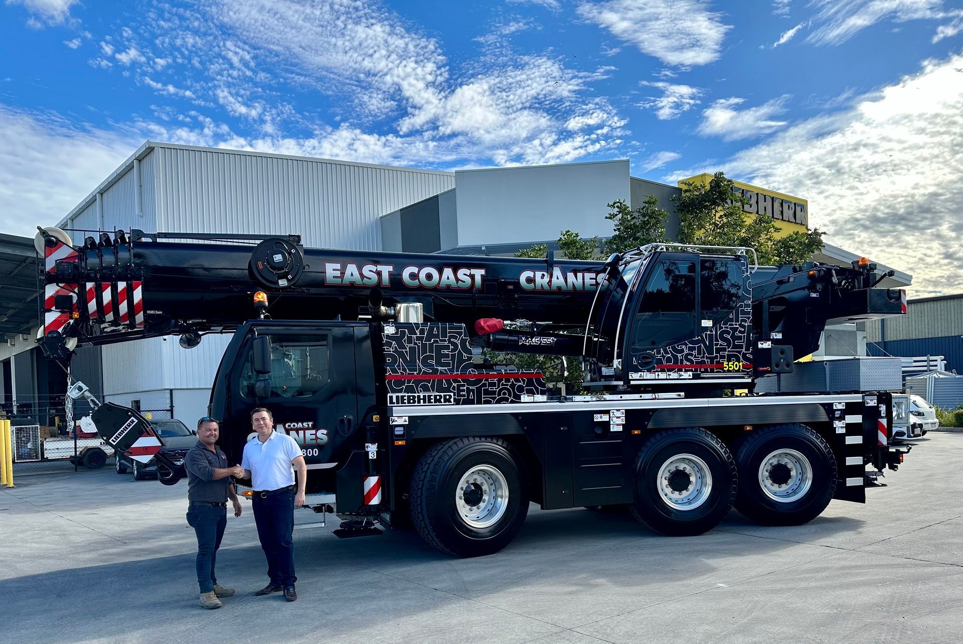 Two Men Stand Beside a Large Black Crane Truck With East Coast Cranes — East Coast Cranes in Ormeau, QLD