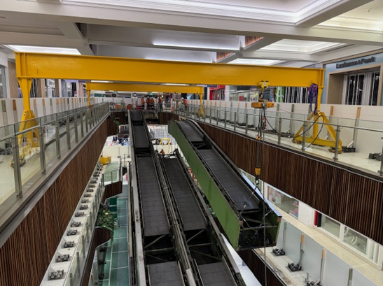 Yellow Overhead Crane Above Two Escalators Under Construction in a Mall — East Coast Cranes in Ormeau, QLD