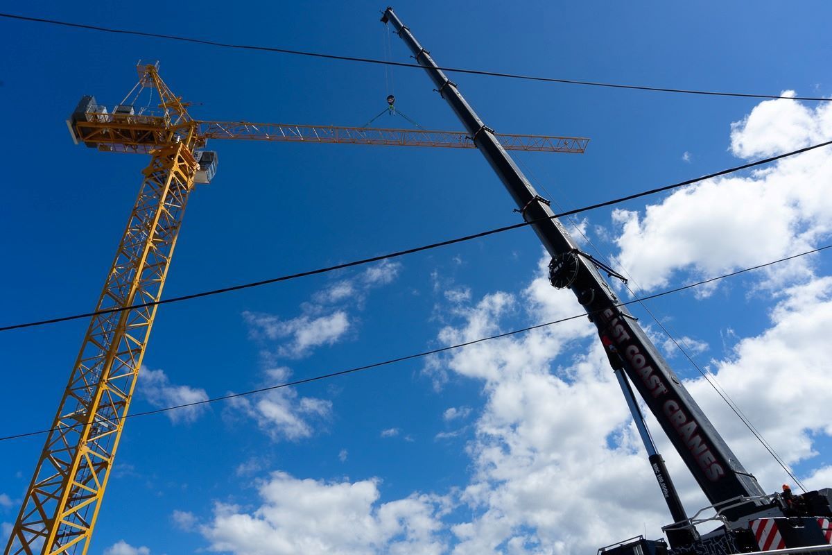 A Yellow Crane and A Black Crane Are Against a Blue Sky with Clouds — East Coast Cranes in Ormeau, QLD