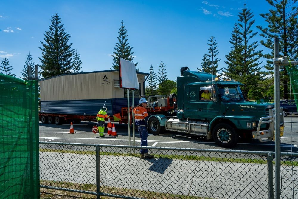 A Green Semi Truck Is Parked on The Side of The Road Next to A Fence — East Coast Cranes in Ormeau, QLD