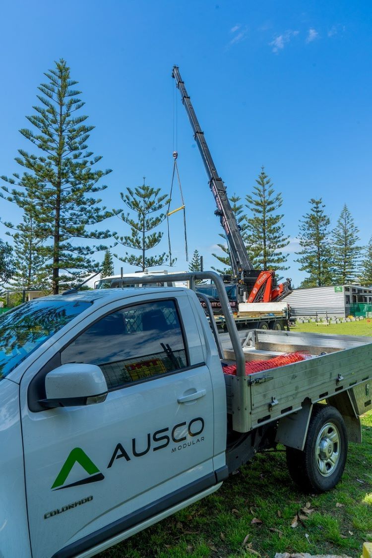 A White Truck with A Crane on The Back Is Parked in A Grassy Field — East Coast Cranes in Ormeau, QLD