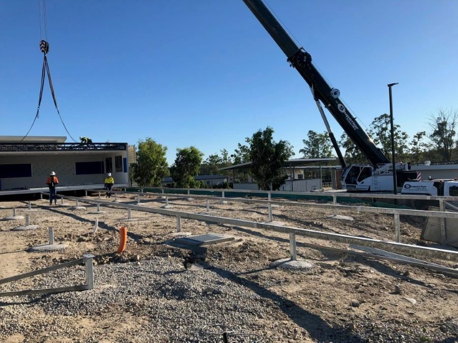 A Large Crane Is Lifting a Building in The Dirt — East Coast Cranes in Ormeau, QLD